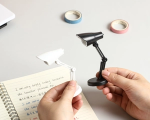 Mini lampes de bureau LED pliables en noir et blanc montrées à l'échelle compacte en main