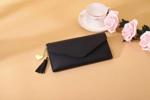 Nahaufnahme der schwarzen Umschlag-Brieftasche mit Herzanhänger und Lederquasten-Detail