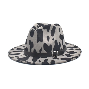 Dettaglio cappello fedora con stampa mucca, cinturino in pelle nera e fibbia argento