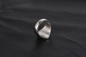 Polished silver titanium steel ring with vintage cross pattern on black leather texture