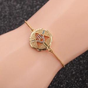 Gold star charm bracelet with colorful zircon inlay on a model's wrist with black background