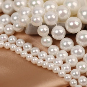 Macro shot of white half-drilled shell pearls with iridescent luster on gold silk fabric