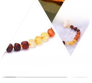 Detail of amber baby necklace showing safety knots between each bead on a white background