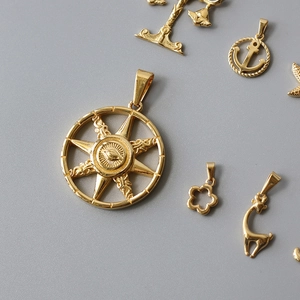 Detailed view of various gold-plated stainless steel pendants including compass and anchor
