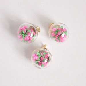 Detailed view of glass ball pendant with pink strawberry slices and gold metal ring loop