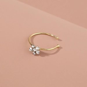 Detail view of a gold nose ring featuring a crystal-encrusted plum blossom floral design