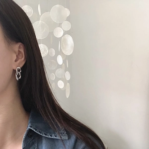 Close-up of silver geometric interlocking link chain earrings on a female model