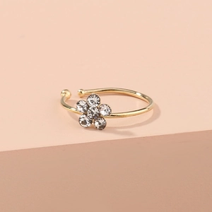 Gold-plated plum blossom nose ring with clear crystals on a warm pastel background