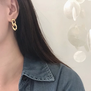 Detail of 18K gold plated double link chain earrings worn by a model on blue denim shirt