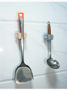 Adhesive wall-mounted mop holder hooks displaying kitchen utensils on white tile
