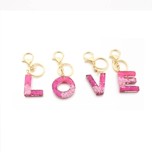 Sparkly resin alphabet keychain with pink glitter sequins spelling LOVE and gold clasp
