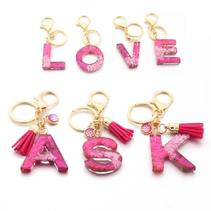 Close-up of resin alphabet keychains with pink sequins, gold hardware and tassels