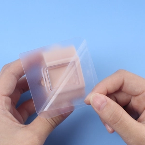 Adhesive wall mount for mops showing transparent film and beige plastic holder base