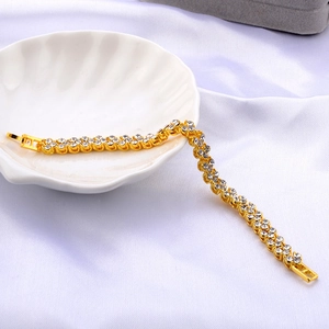 Detail of double-row cubic zirconia gold bracelet on a shell tray with white silk
