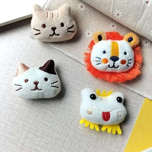 Cute plush animal pins featuring cartoon cat, lion, and frog on rustic linen background
