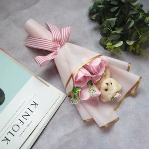Detailed top view of pink soap roses and small teddy bear bouquet in gold-edged wrap
