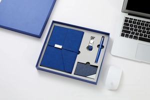 Detail of navy blue business gift set featuring leather notebook, pen, and keychain in box