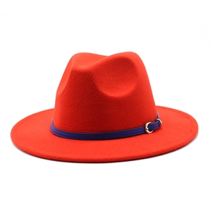 Detail of red wool fedora hat featuring a navy leather band and golden metal buckle clasp