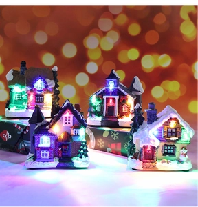 Close-up of glowing resin Christmas village houses with colorful LED lights on gift boxes