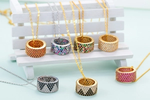 Detailed view of colorful rhinestone inlaid ring pendants on a white wooden bench