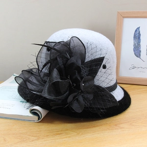 Close-up of vintage wool cloche hat with black mesh, floral detail, and feather accents