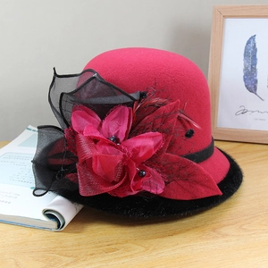 Detail of red wool felt bowler hat featuring elegant fabric flower and black mesh veil