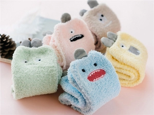 Folded colorful coral fleece socks with cute cartoon monster faces and 3D ears