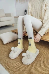Detail of yellow monster coral fleece socks with cute cartoon ears and white plush slippers