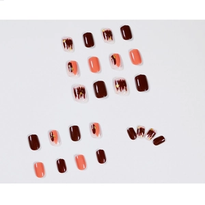 Short square press-on nails in burgundy marble and coral orange with gold foil accents