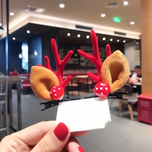 Detail of Christmas reindeer antler hair clip with brown plush ears and red accents