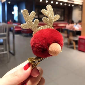 Close-up of a Christmas reindeer hair clip with red plush ball and gold glitter antlers