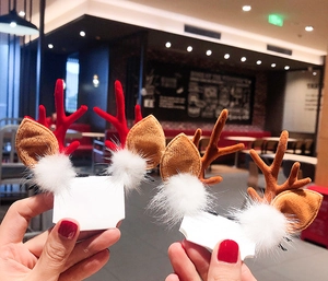 Detail showing plush Christmas reindeer antler hair clips with festive white pom-poms