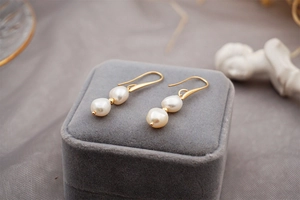 Detailed macro view of baroque pearl earrings with golden hooks and natural texture