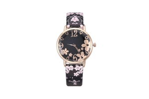 Close-up of artistic floral watch face with rose gold numerals and cherry blossom leather strap