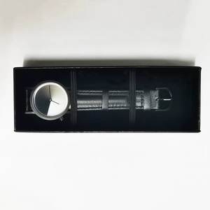 Close-up of minimalist leather strap watch with gradient dial in a black gift box