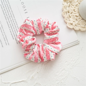 Detail of pink striped velvet scrunchie with teal polka dots on a vintage magazine