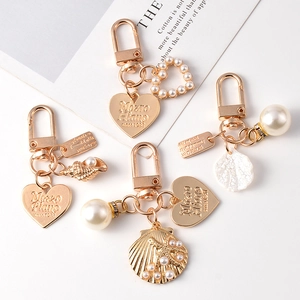 Golden keychain with heart, sea shell, and pearl charms for bags or Airpods