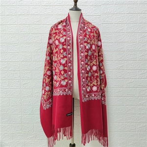 Close-up of red cashmere shawl with multi-color floral embroidery and tassel fringe details