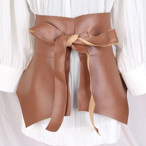 Brown faux leather corset belt with ruffle hem and bow tie detail over white dress