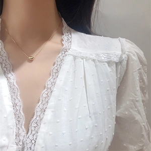 Elegant gold bean pendant necklace in stainless steel worn by a model on collarbone