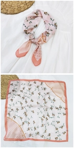 Dettaglio di un foulard di seta quadrato con motivi floreali su base rosa e bordi corallo