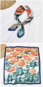 Dettaglio di un foulard di seta con motivo a girasole arancione e bordo blu scuro