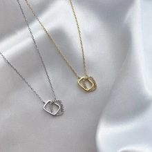 Close-up of gold and silver interlocking square pendant necklaces with cubic zirconia on satin