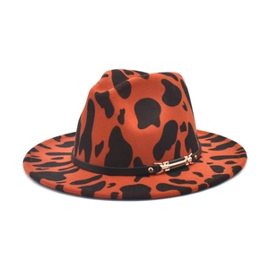 Detailed view of cow print fedora hat featuring a black leather band and gold buckle