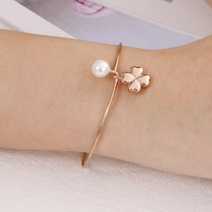 Minimalist rose gold stainless steel bangle with white pearl and clover charm on wrist