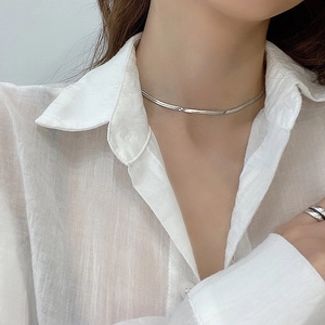 Close-up of a minimalist silver flat snake chain necklace worn on a woman's neck