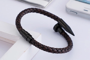 Macro detail of brown woven leather cord and black steel nail clasp on punk style bracelet