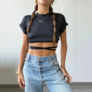 Sexy black crop top with crew neck and waist tie detail paired with blue jeans