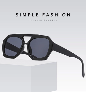 Vue détaillée de lunettes de soleil géométriques noires avec double pont sur bloc blanc