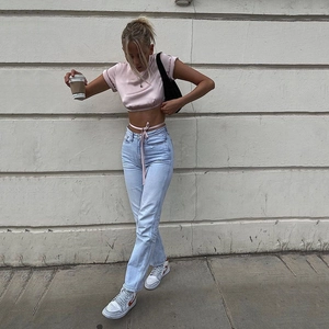Street style shot of pink crop top with waist ties and high-waisted denim jeans